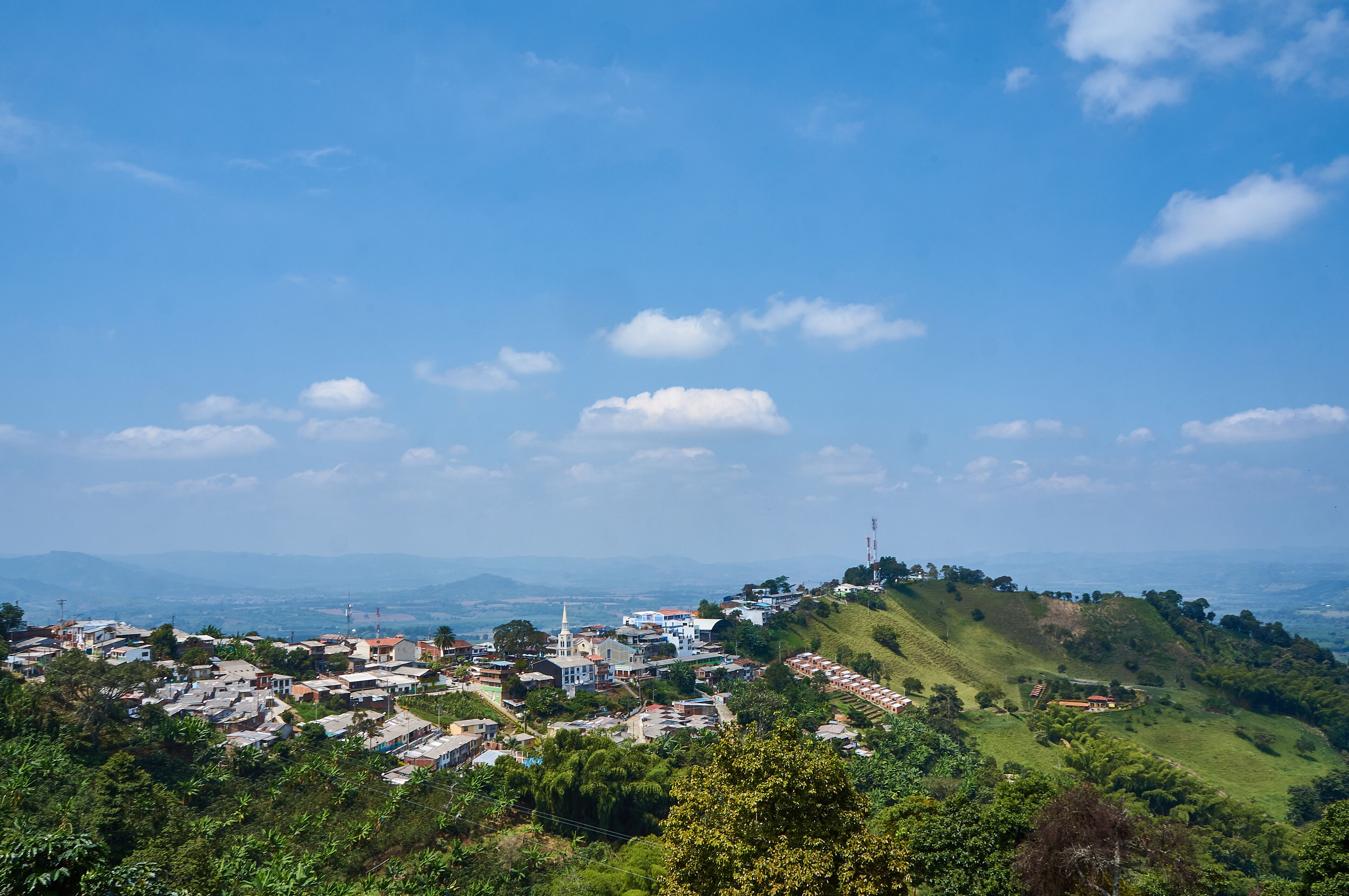 A town nestled in a valley with a prominent church and rolling hills in the background.