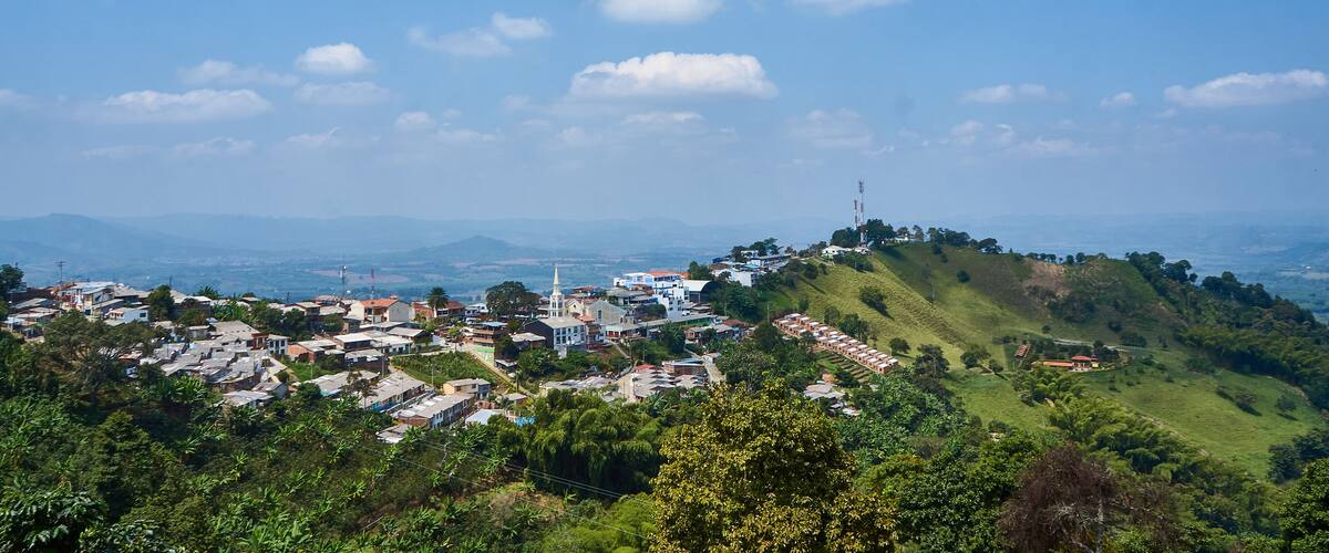 A town nestled in a valley with a prominent church and rolling hills in the background.