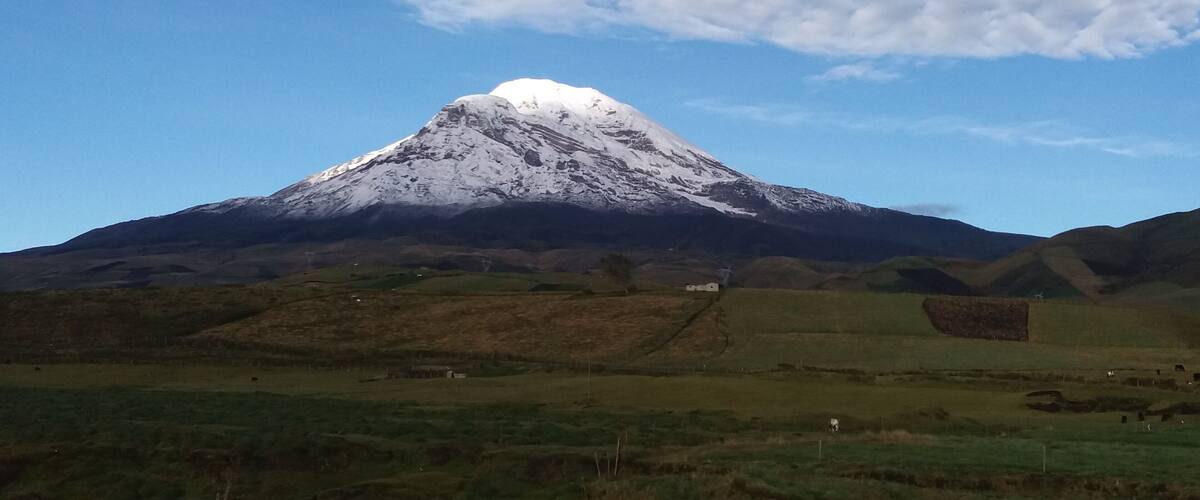 A snow-capped mountain with a clear sky and scattered clouds.