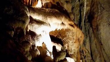 A cave with stalactites and stalagmites illuminated by artificial light.
