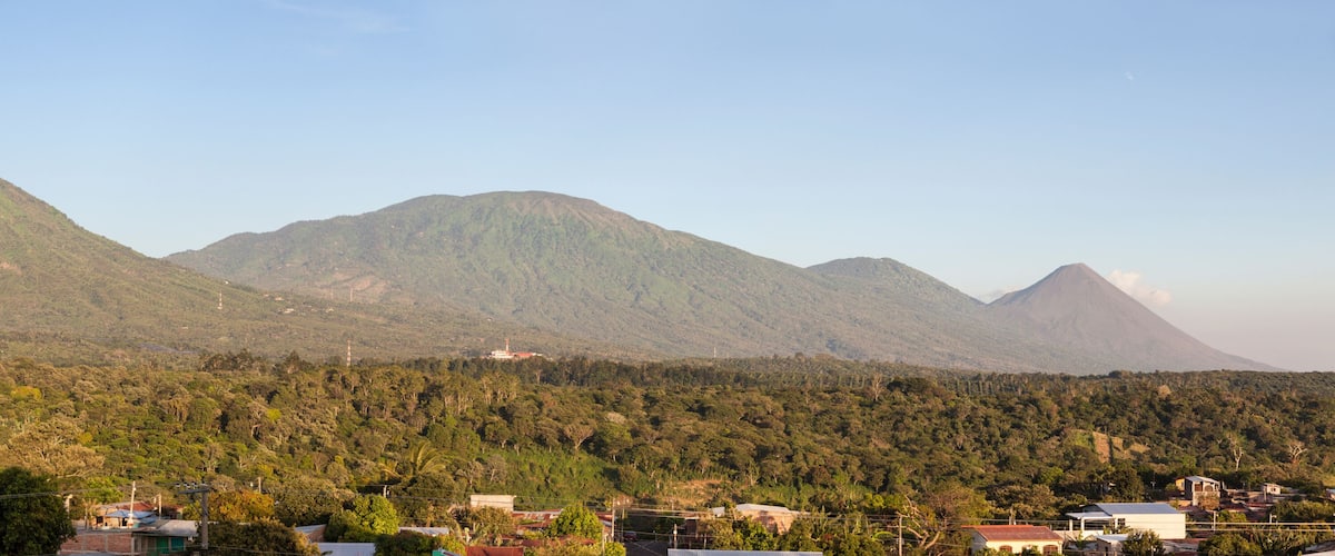 A mountainous landscape with dense forests and scattered houses.