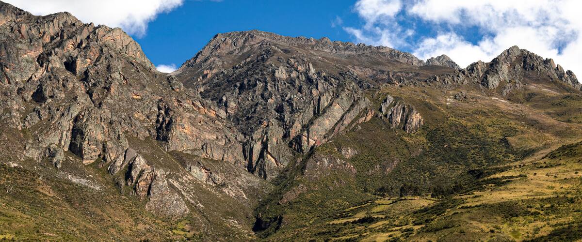 Rugged mountains with rocky peaks and sparse vegetation under a partly cloudy sky.