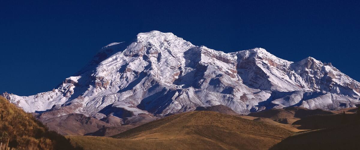 A snow-capped mountain with rugged terrain and a clear blue sky.