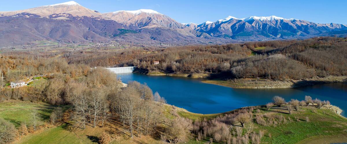 A mountainous landscape with a lake, a small village, and snow-capped peaks.