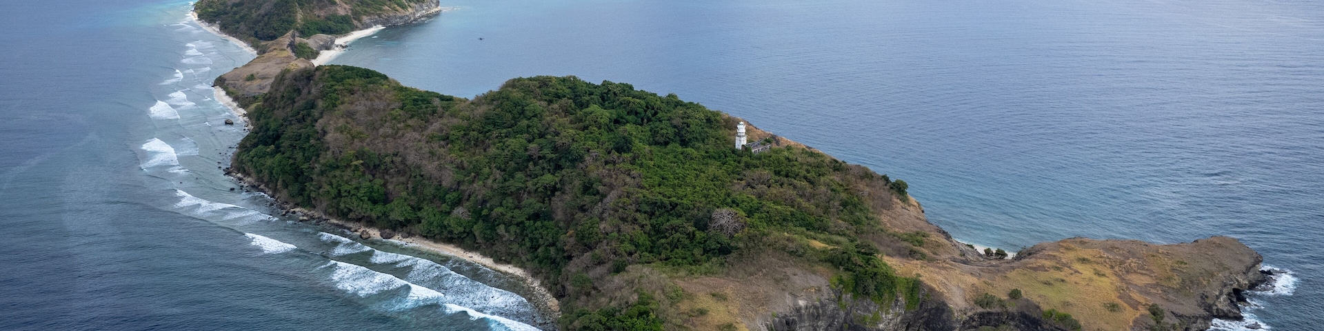 Vista aérea de una isla costera con terreno accidentado y un faro.