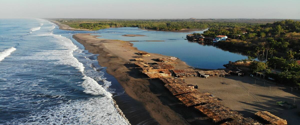A coastal landscape with a beach, a river, and scattered buildings.