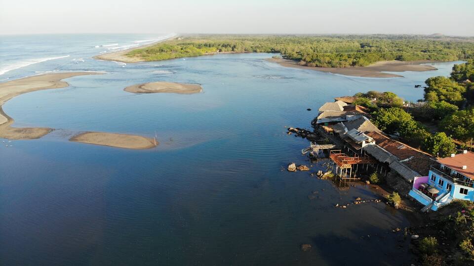 A coastal town with thatched-roof houses and a river.