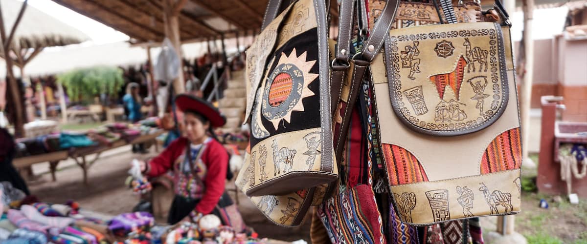 A market stall with colorful textiles and bags with intricate designs.