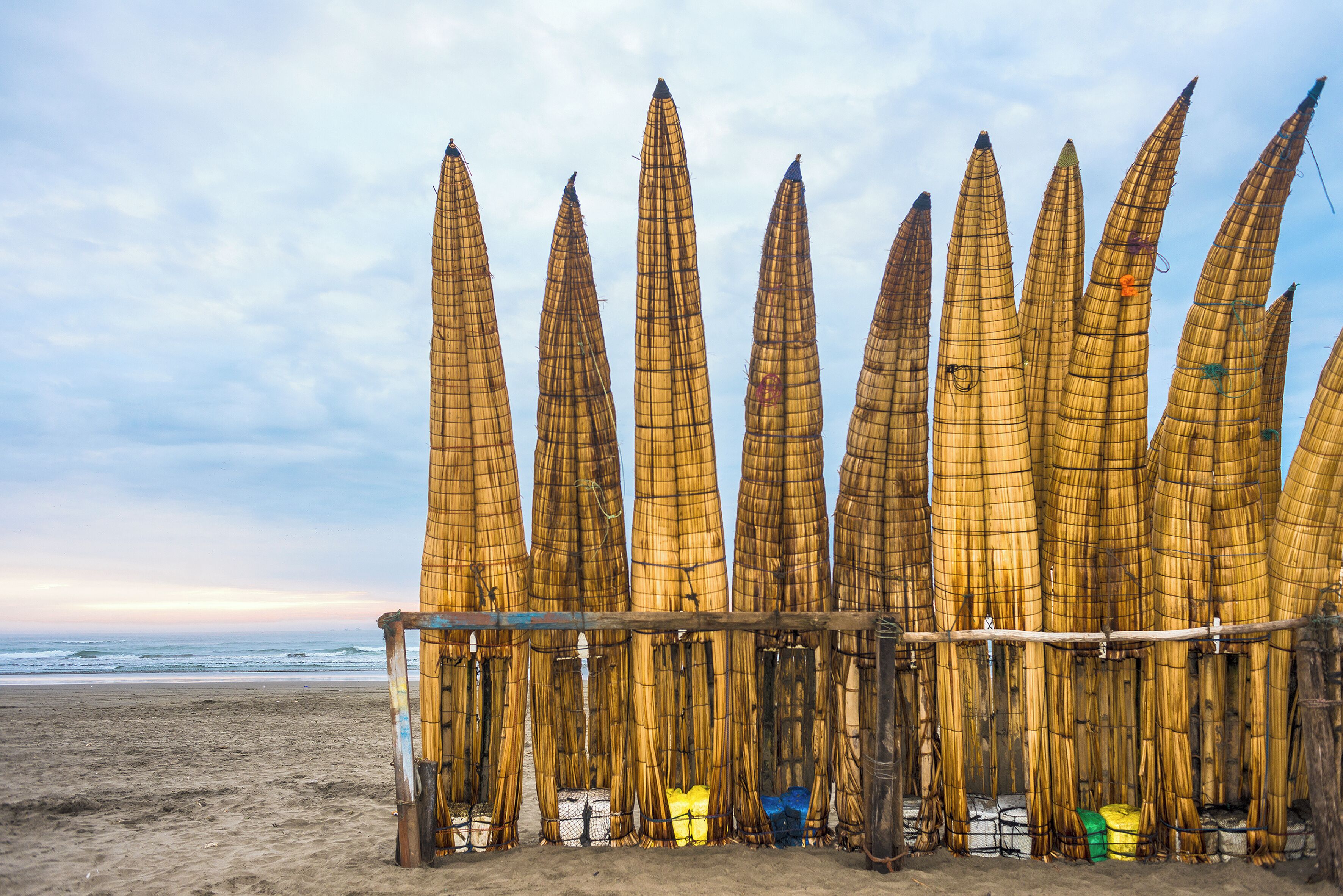 A beach with bamboo structures and a wooden fence.