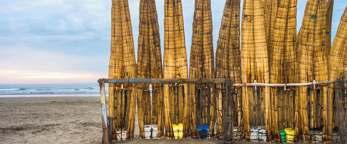 A beach with bamboo structures and a wooden fence.