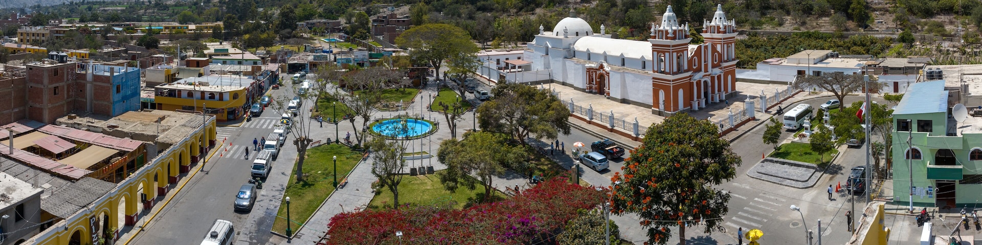 A town with a central plaza, a church, and mountains in the background.