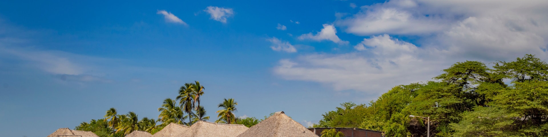 Thatched roof restaurants near the beach, thatched roof restaurant near wooden boats with blue sky, nicaragua restaurants near the beach
