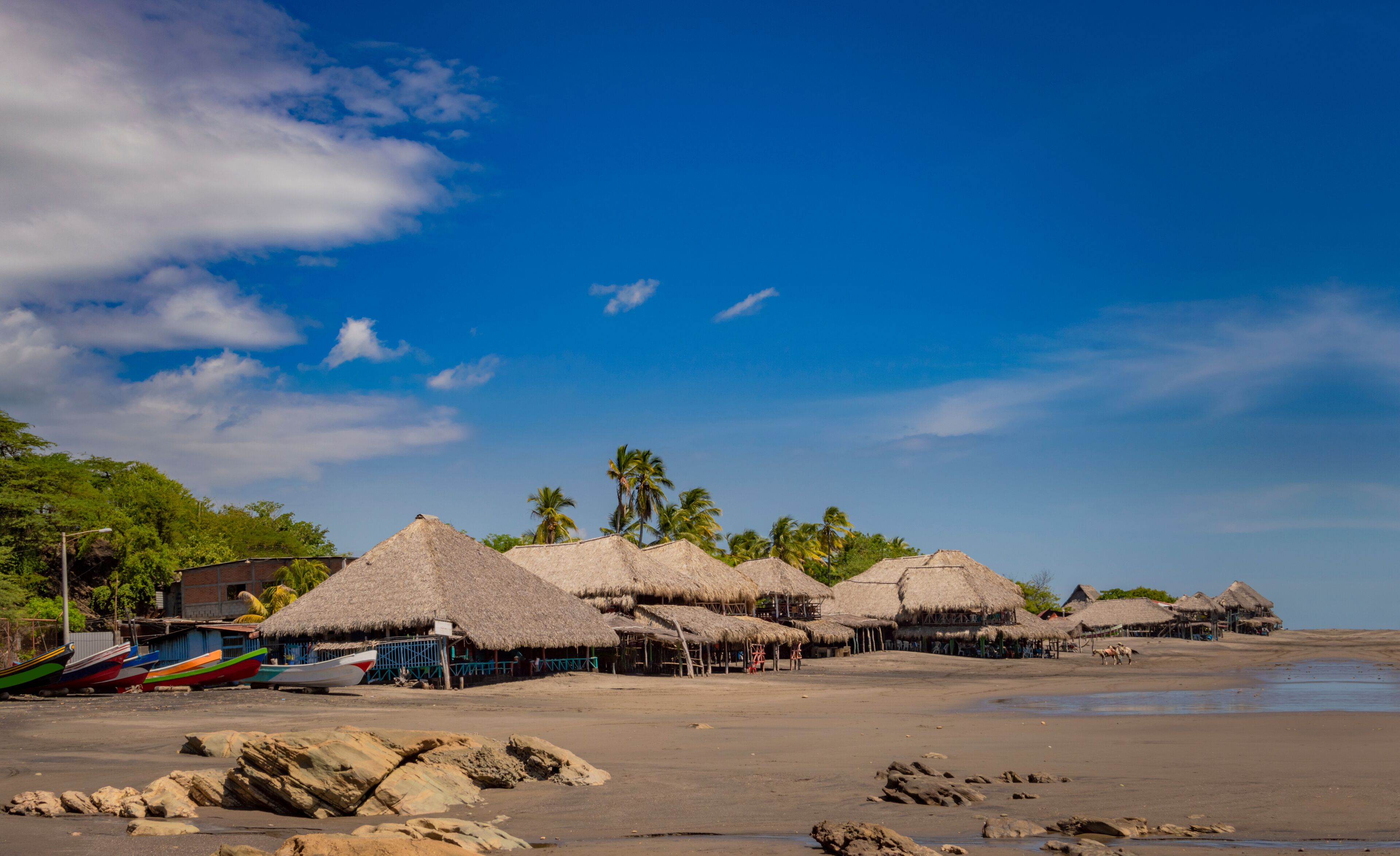 Thatched roof restaurants near the beach, thatched roof restaurant near wooden boats with blue sky, nicaragua restaurants near the beach