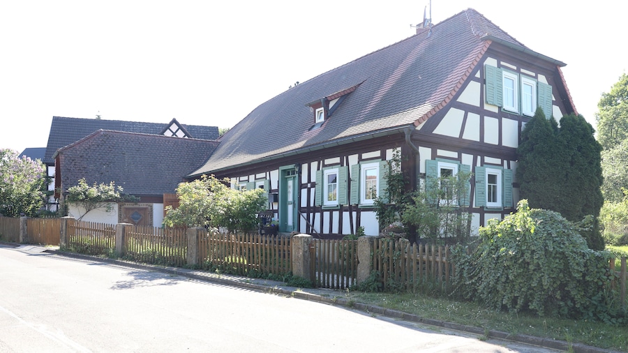 A traditional half-timbered house with a sloped roof and green shutters.