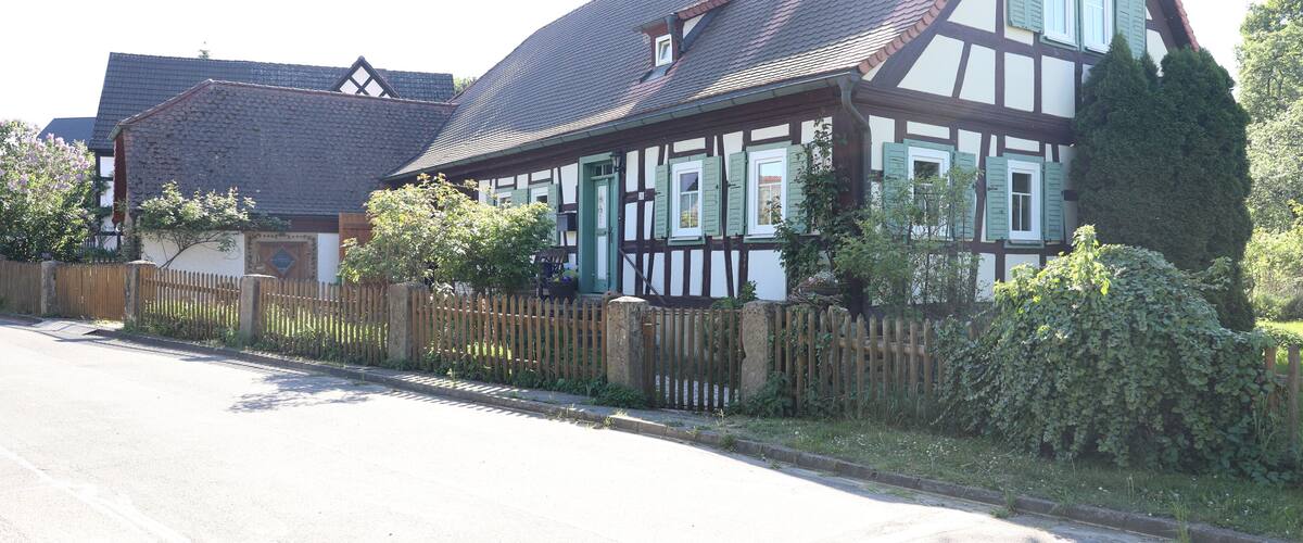 A traditional half-timbered house with a sloped roof and green shutters.