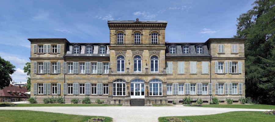 Un grand bâtiment historique à l’architecture symétrique, doté de nombreuses fenêtres et d’une entrée centrale.