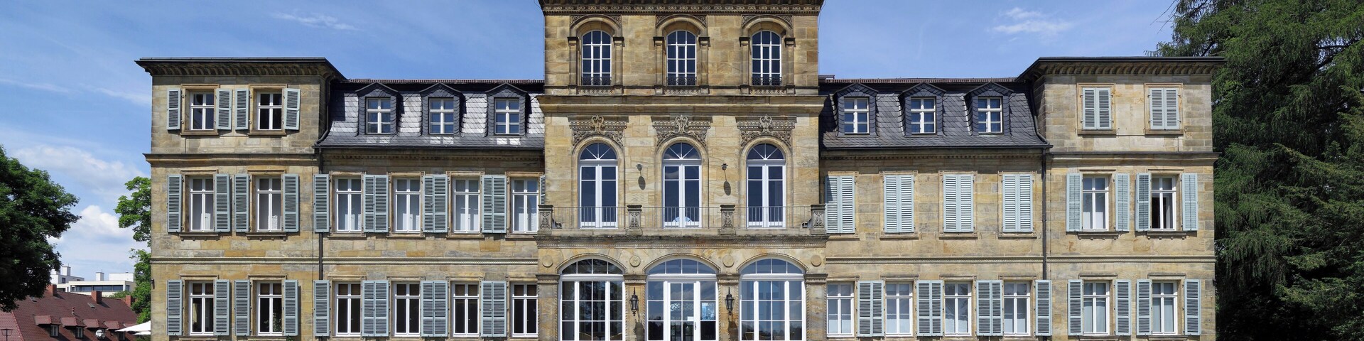 Un grand bâtiment historique à l’architecture symétrique, doté de nombreuses fenêtres et d’une entrée centrale.