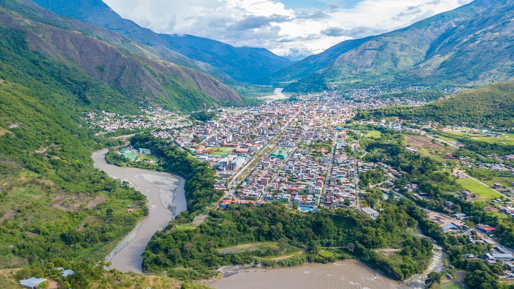 Une ville nichée dans une vallée, traversée par une rivière et entourée de montagnes.