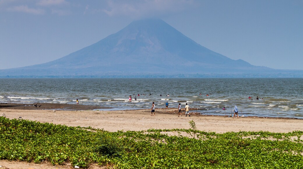 RIVAS, NICARAGUA - MAY 1, 2016: People swim in Lago Cocibolca (Nicaragua Lake) near San Jorge village, Nicaragua. Volcano Concepcion in the background.