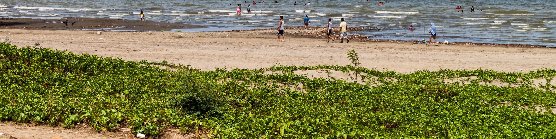 RIVAS, NICARAGUA - MAY 1, 2016: People swim in Lago Cocibolca (Nicaragua Lake) near San Jorge village, Nicaragua. Volcano Concepcion in the background.
