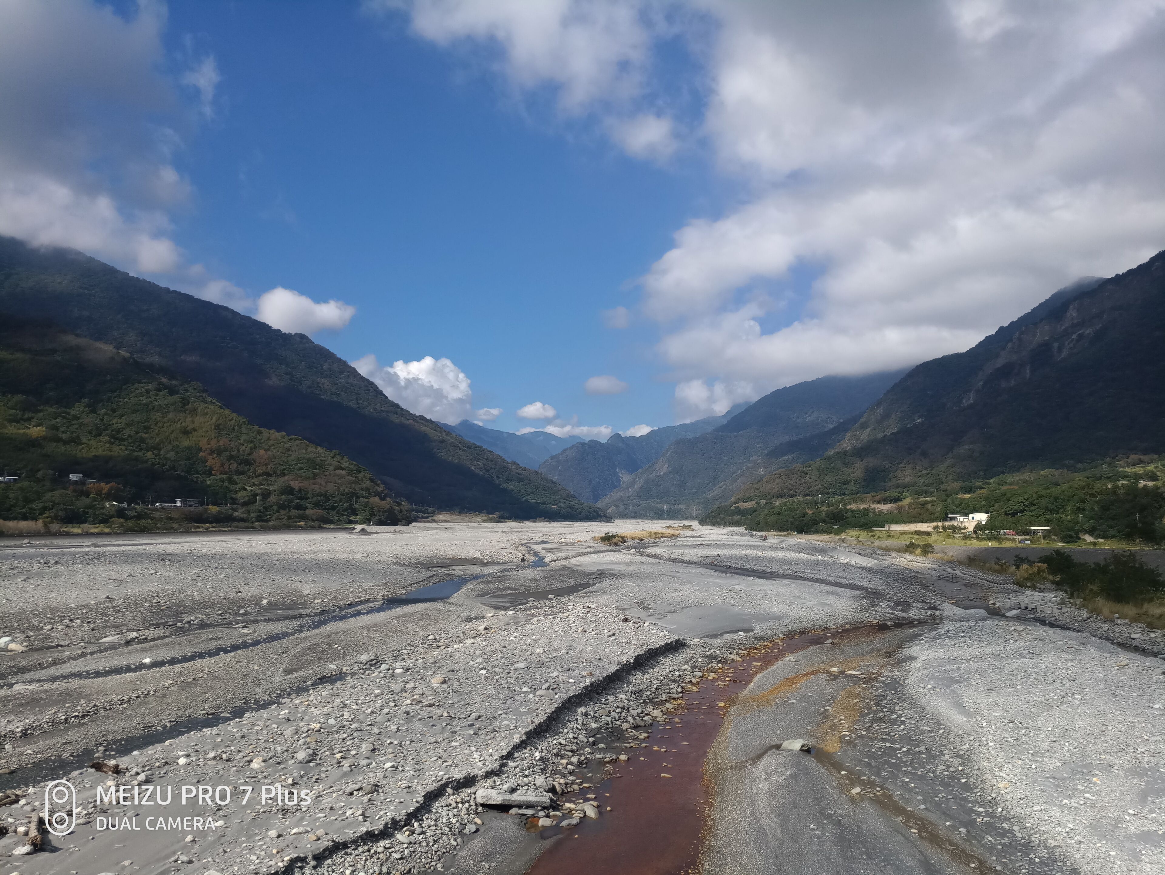 A mountainous landscape with a riverbed and scattered rocks.