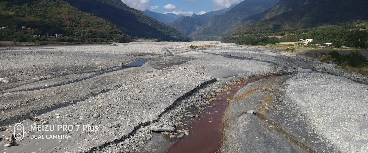 A mountainous landscape with a riverbed and scattered rocks.