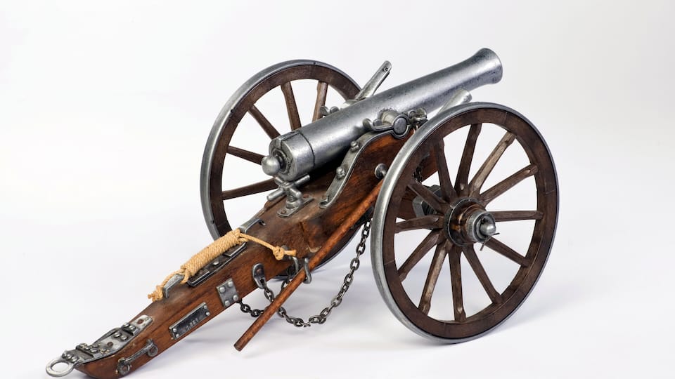 A historical cannon with wooden wheels and a leather strap.