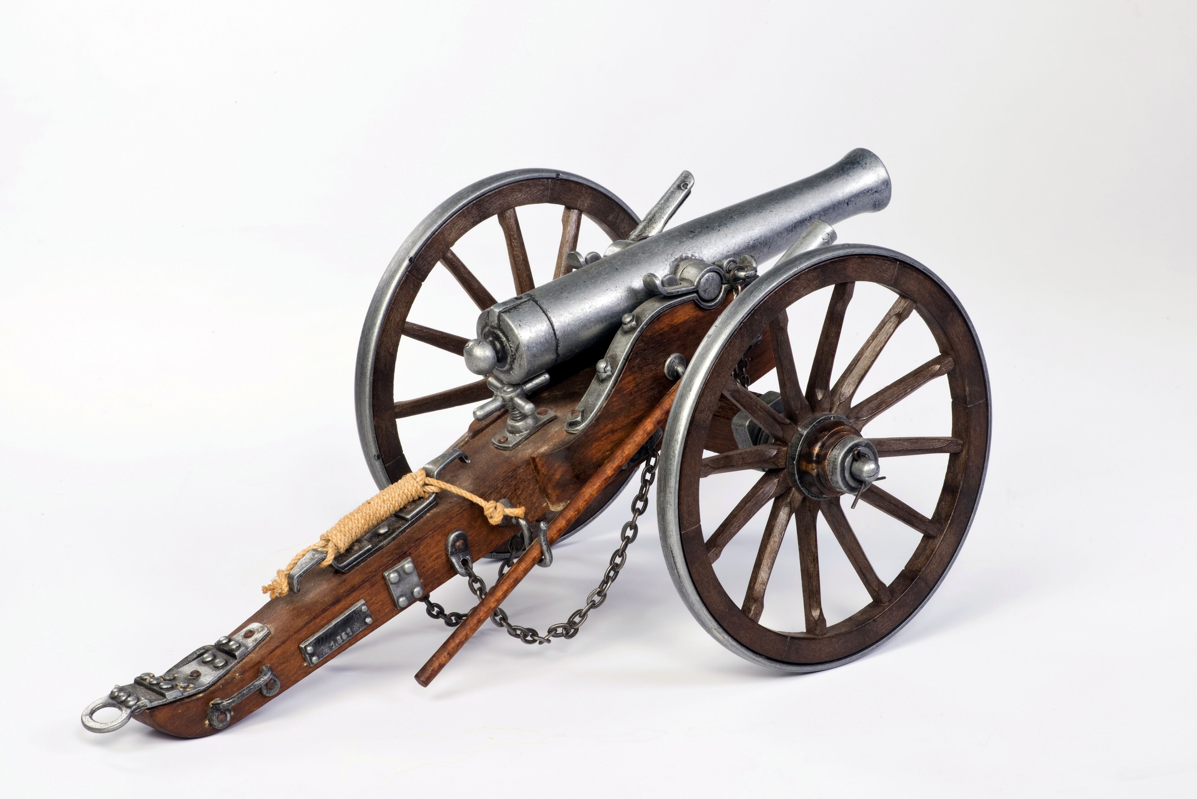 A historical cannon with wooden wheels and a leather strap.