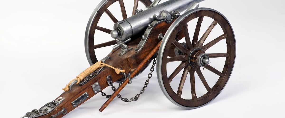 A historical cannon with wooden wheels and a leather strap.