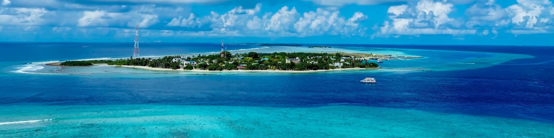 A tropical island with clear turquoise waters, a white sandy beach, and a small boat.