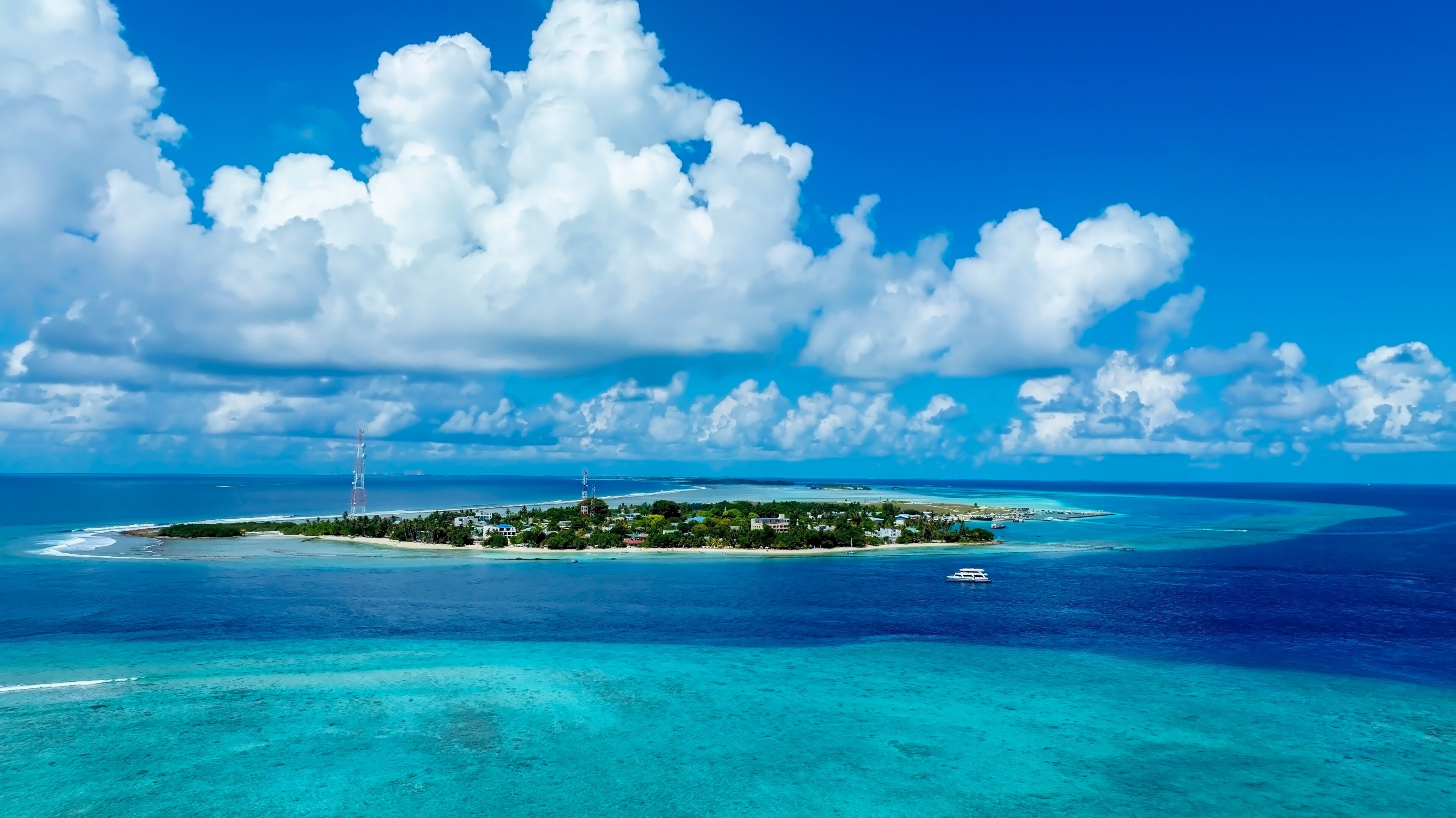 A tropical island with clear turquoise waters, a white sandy beach, and a small boat.