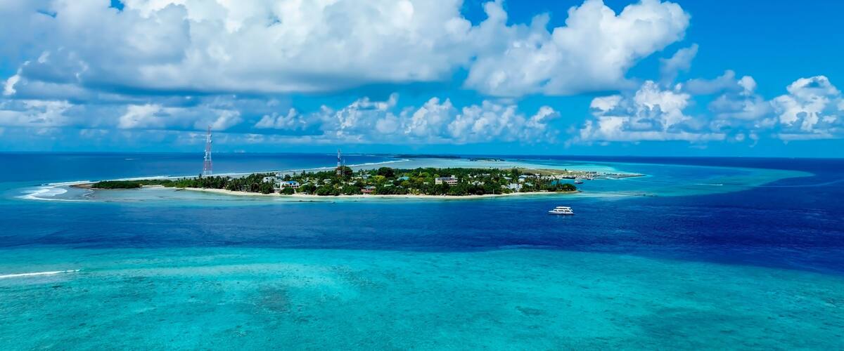 A tropical island with clear turquoise waters, a white sandy beach, and a small boat.