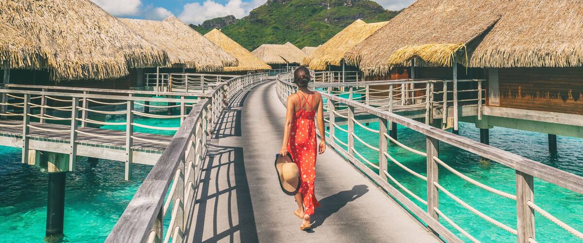 A wooden walkway with thatched-roof overwater bungalows in turquoise waters.