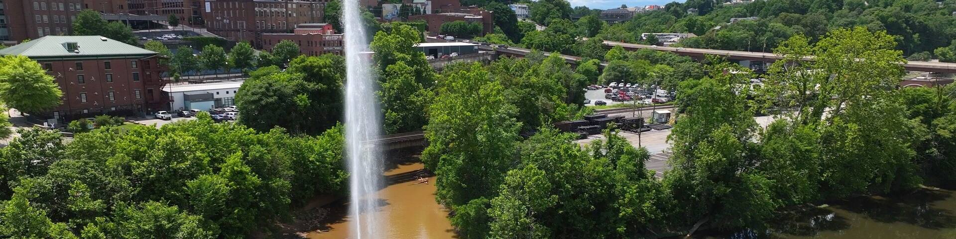 Langley Fountain with rainbow at Lynchburg, VA in James River beside downtown city skyline is historic landmark