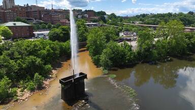 Langley Fountain with rainbow at Lynchburg, VA in James River beside downtown city skyline is historic landmark