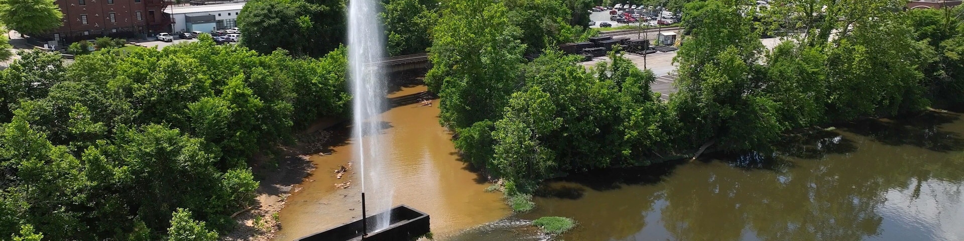 Langley Fountain with rainbow at Lynchburg, VA in James River beside downtown city skyline is historic landmark