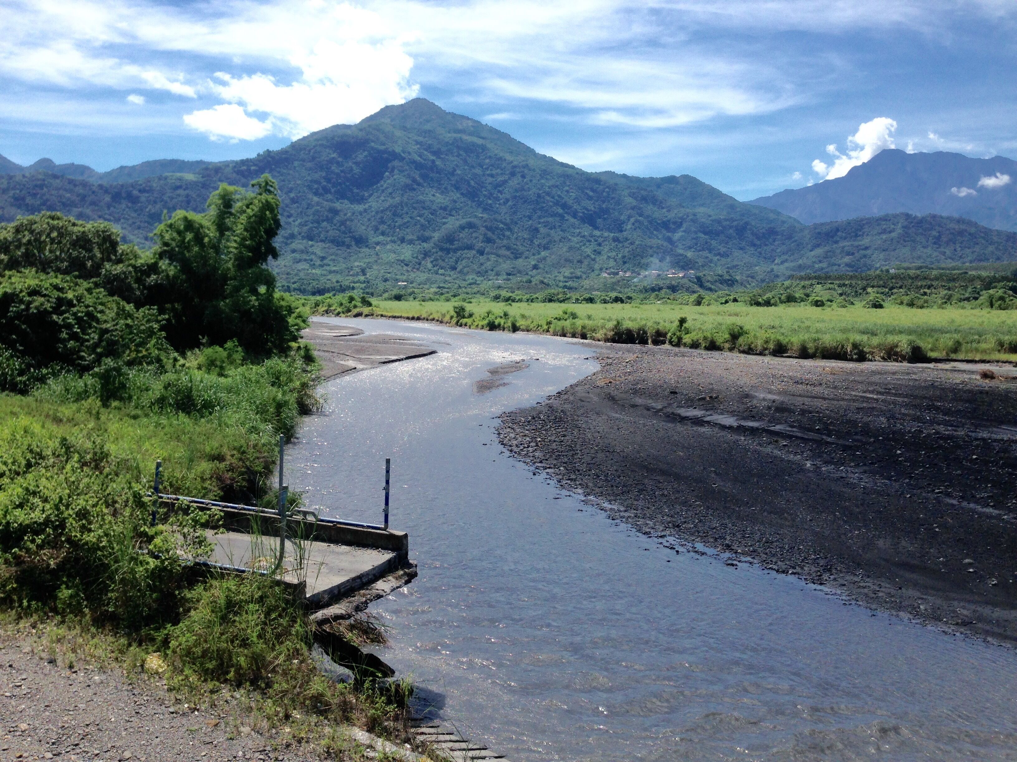A river flowing through a lush valley with mountains in the background.