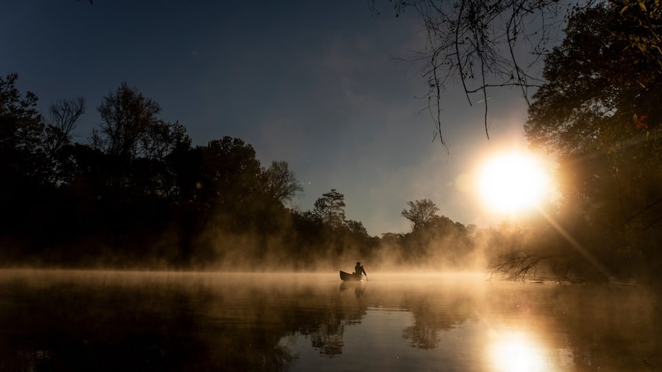 Sunrise canoe ride on foggy river.