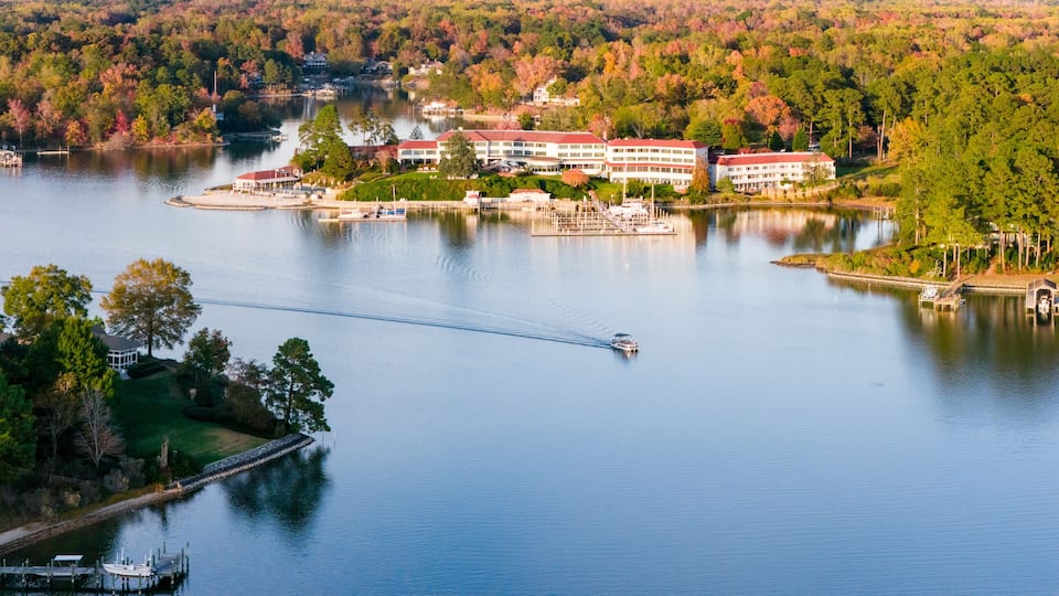 A lake with a dock, a boat, and a building with a red roof.