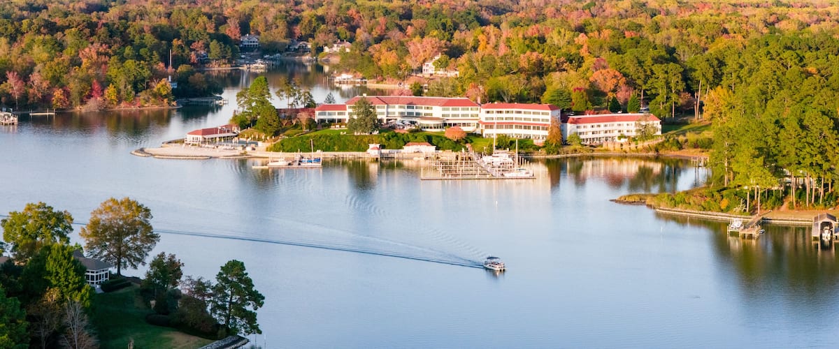 A lake with a dock, a boat, and a building with a red roof.