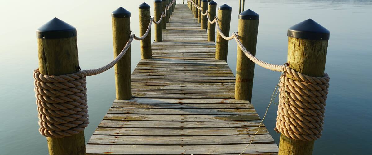 A wooden pier extending into calm water with a rope barrier at both ends.