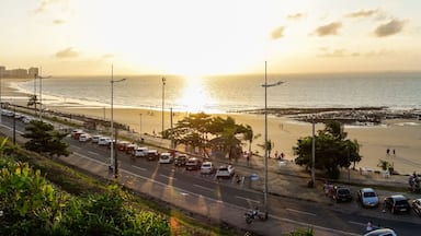 A coastal road with parked cars and a beach in the background.
