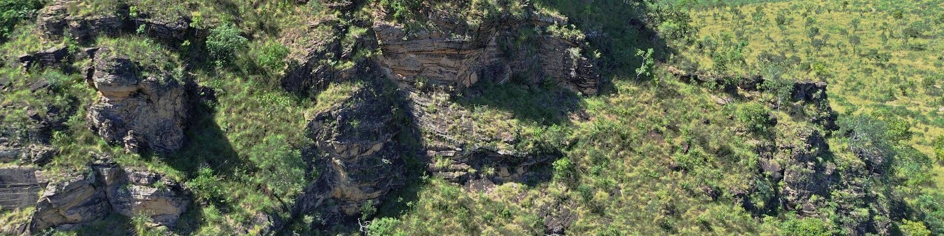 Geoloigical formatiom, hill covered by green, eroded sandstone rocks exposed reddish ground. Cerrado vegetation in Chapada das Mesas, Maranhao