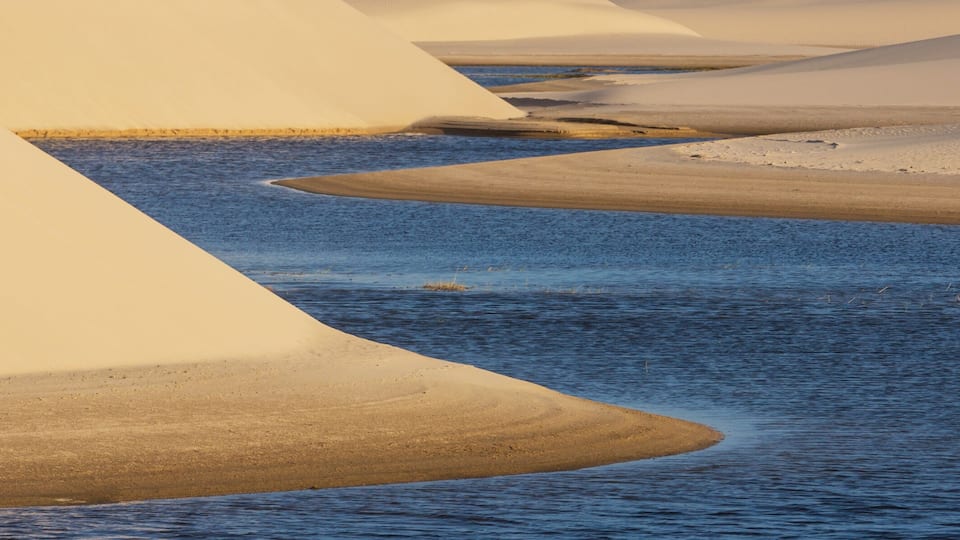 A desert landscape with sand dunes and a body of water.