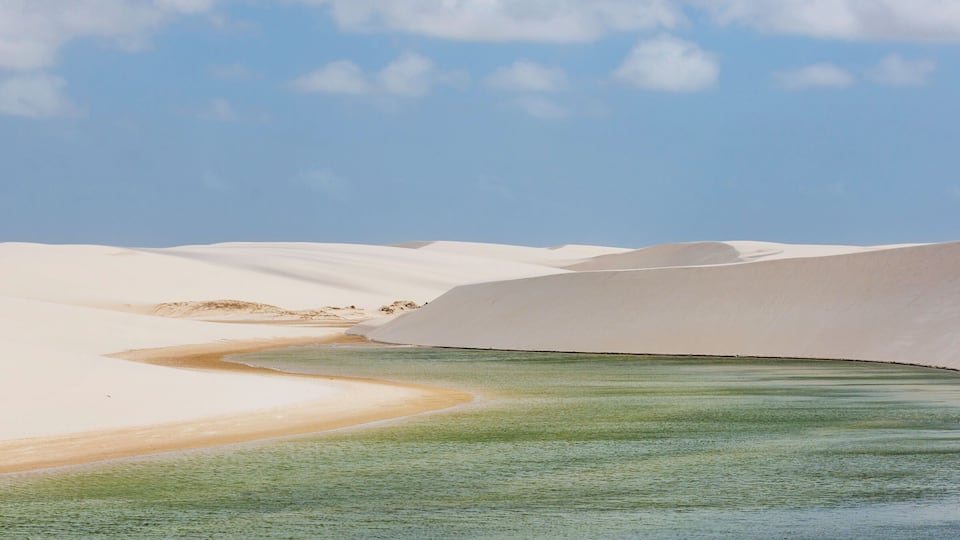 A desert landscape with sand dunes and a river.