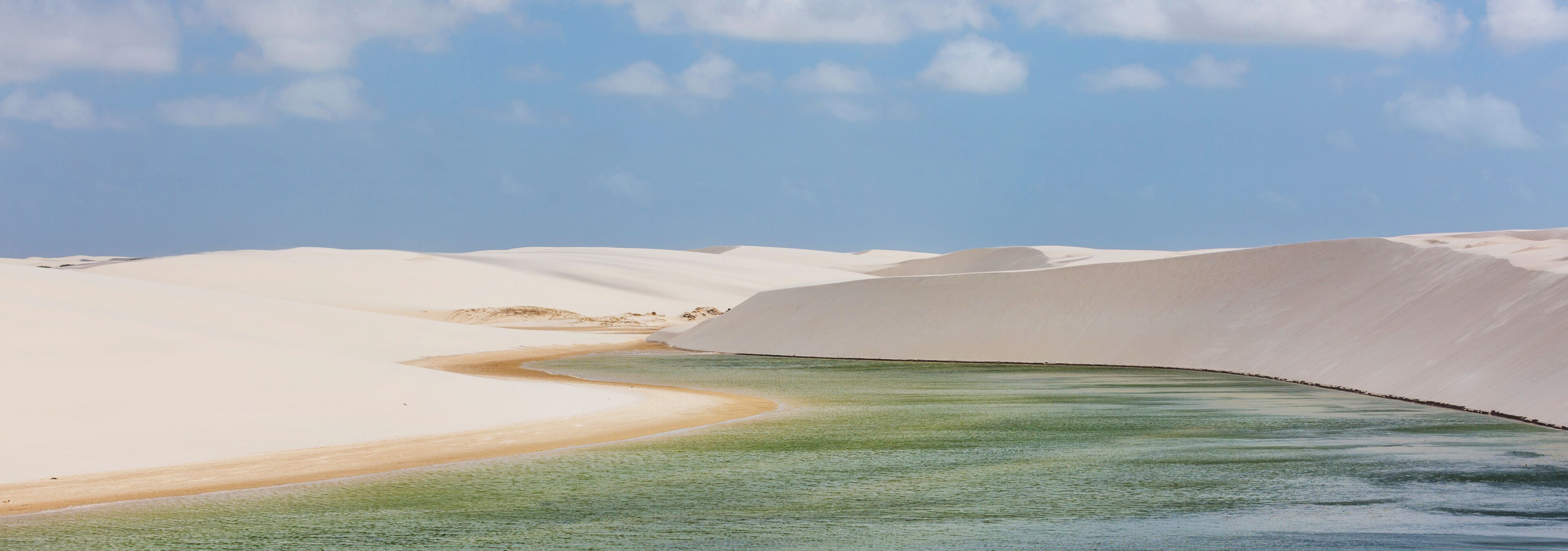 A desert landscape with sand dunes and a river.
