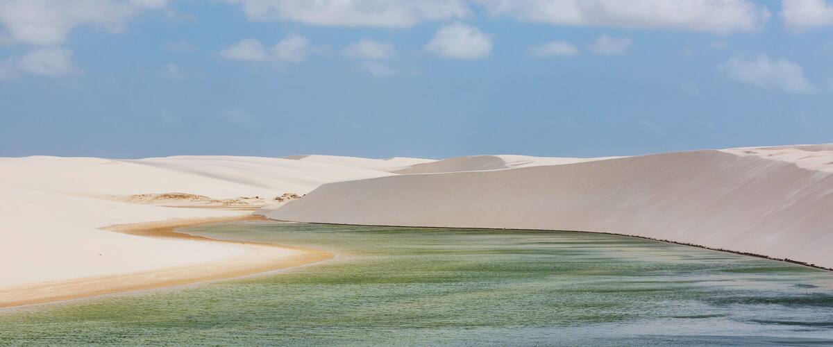 A desert landscape with sand dunes and a river.