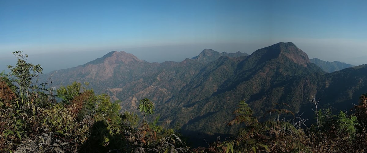 A mountainous landscape with dense vegetation and a clear sky.