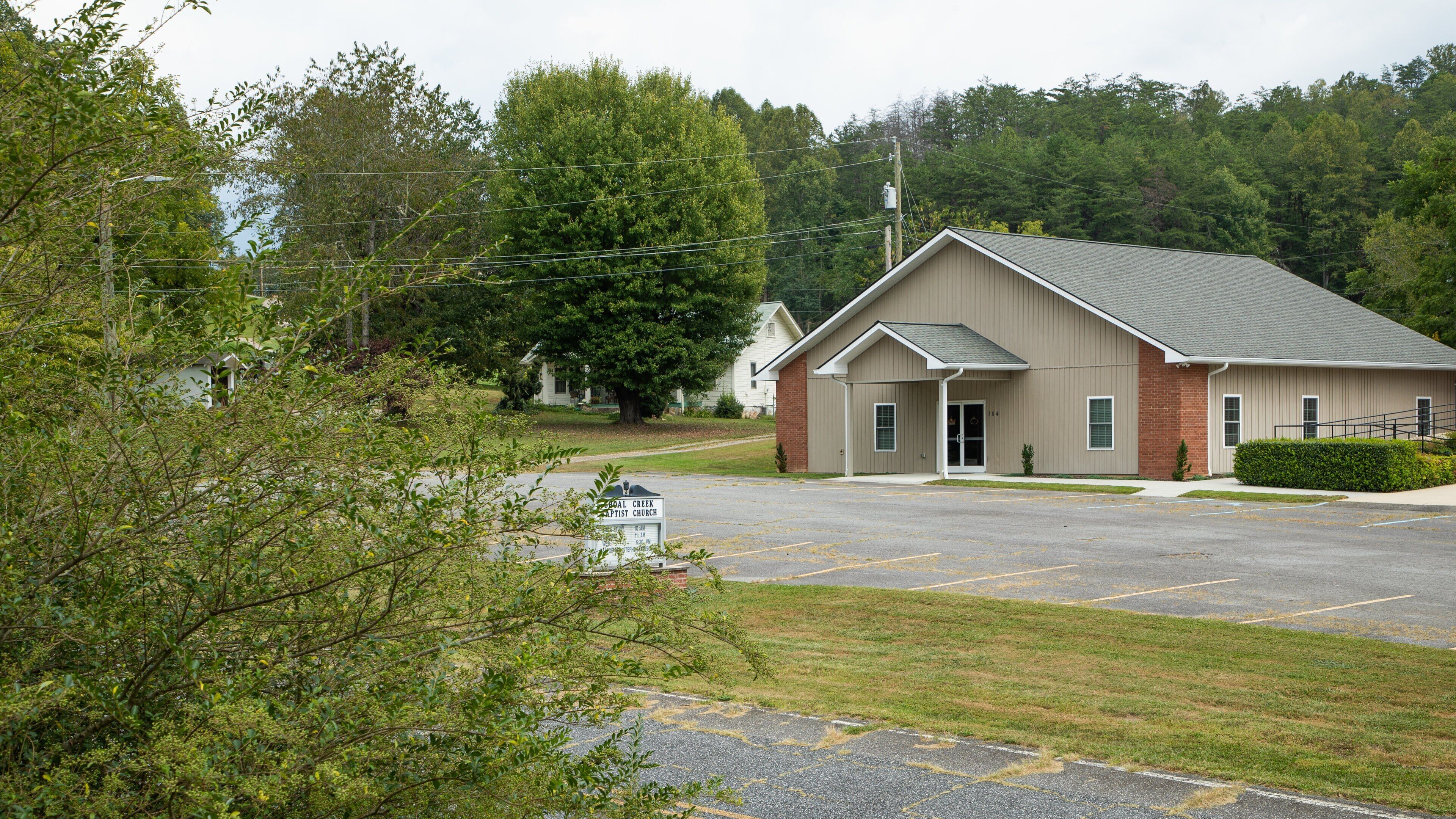 A church building with a parking lot and surrounding greenery.