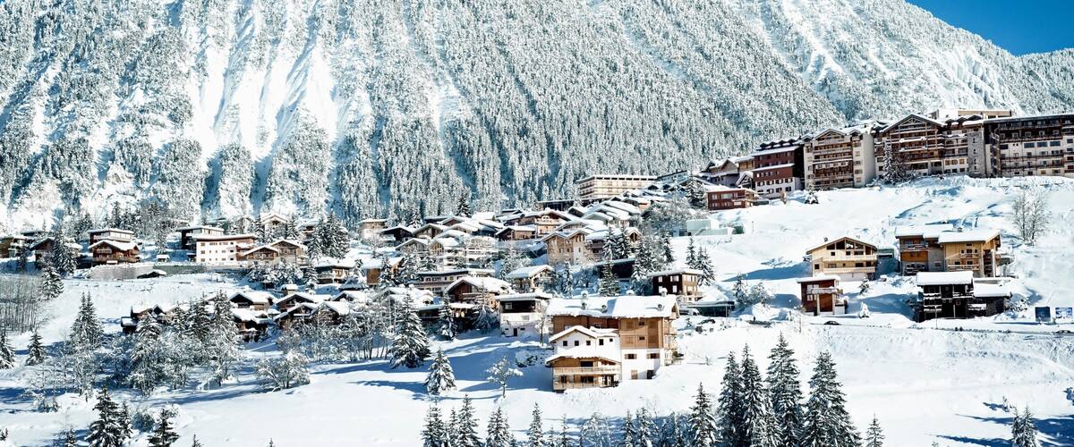 A snow-covered mountain with a ski resort and buildings.